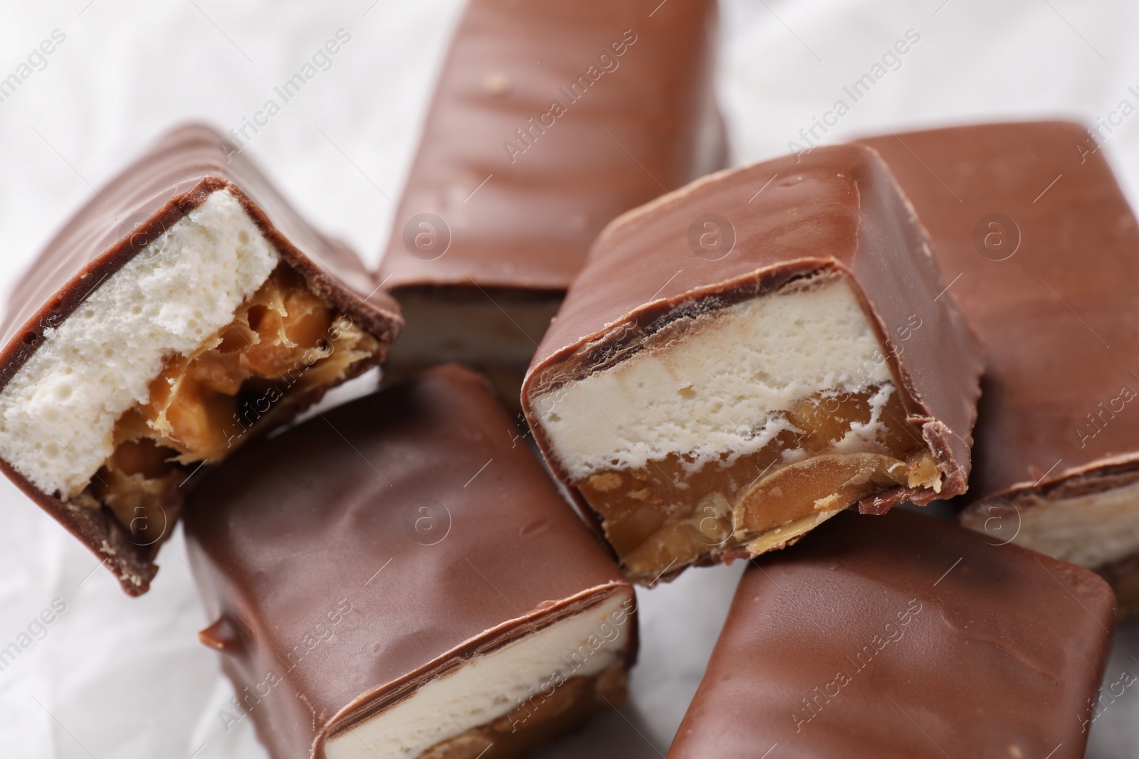 Photo of Tasty chocolate bars with nougat and nuts on white background, closeup