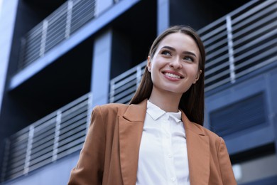 Photo of Young woman in formal clothes near building outdoors, space for text