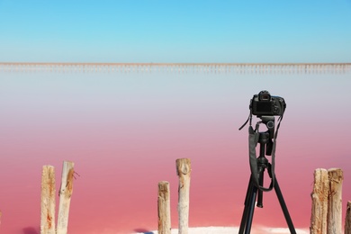 Professional camera with tripod near pink lake