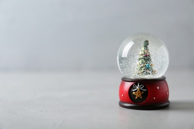 Snow globe with Christmas tree on grey table, space for text