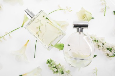 Photo of Luxury perfumes on spring floral decor, top view