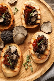 Photo of Delicious bruschettas with truffle sauce and sun dried tomatoes on wooden table, top view