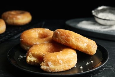 Photo of Sweet delicious glazed donuts on black table