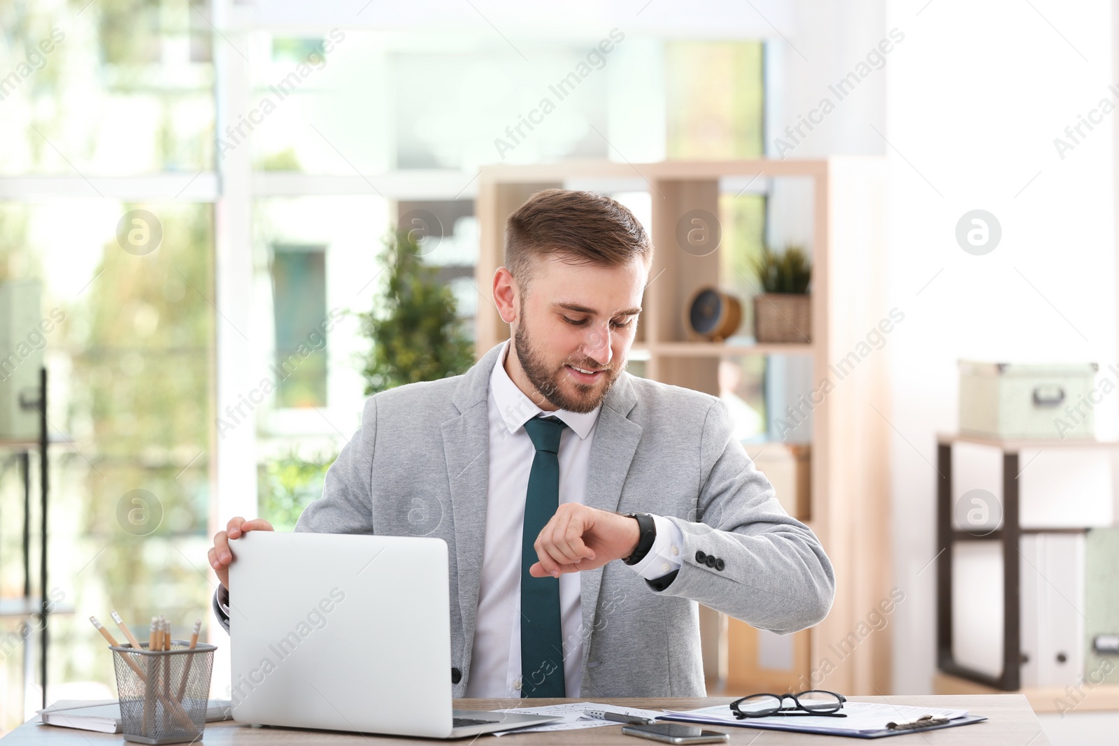 Photo of Young businessman using laptop at table in office