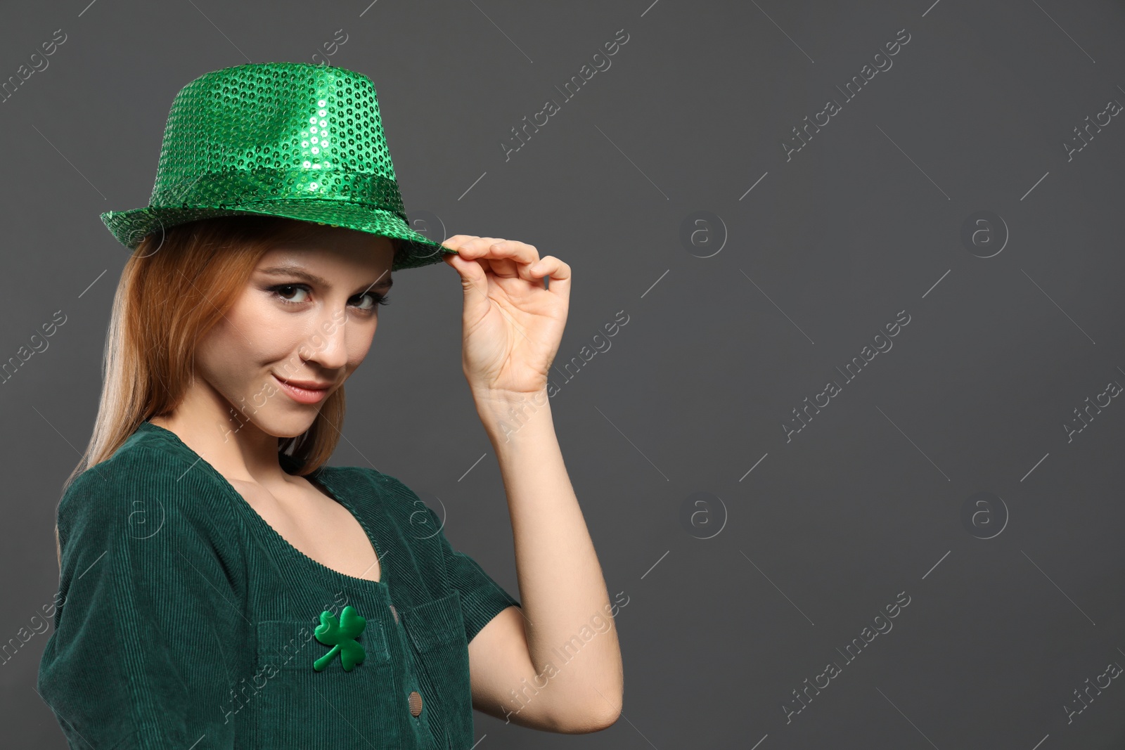 Photo of Young woman in green outfit on grey background, space for text. St. Patrick's Day celebration