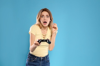 Photo of Emotional young woman playing video games with controller on color background. Space for text