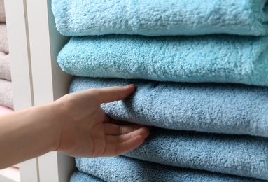 Photo of Woman taking towel from shelf, closeup view