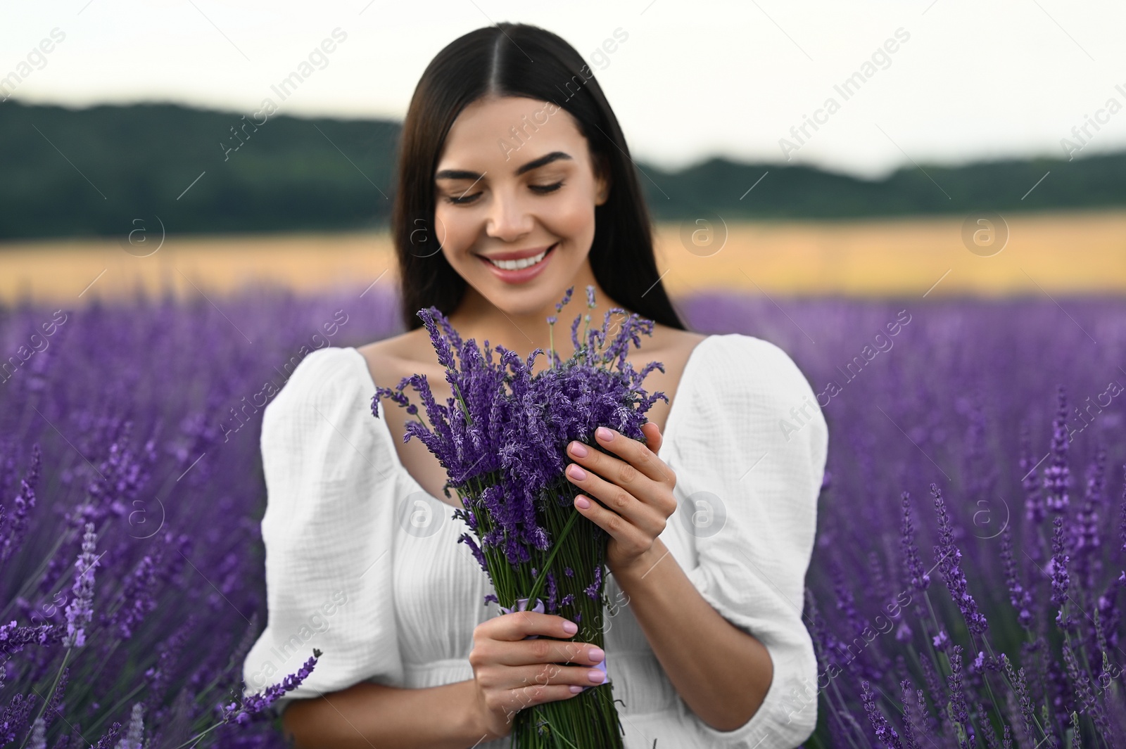 Photo of Beautiful young woman with bouquet in lavender field