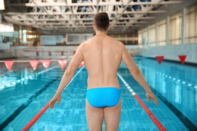 Young athletic man standing near swimming pool