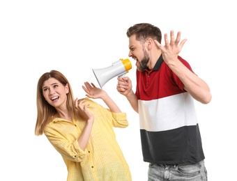 Young man with megaphone shouting at woman on white background