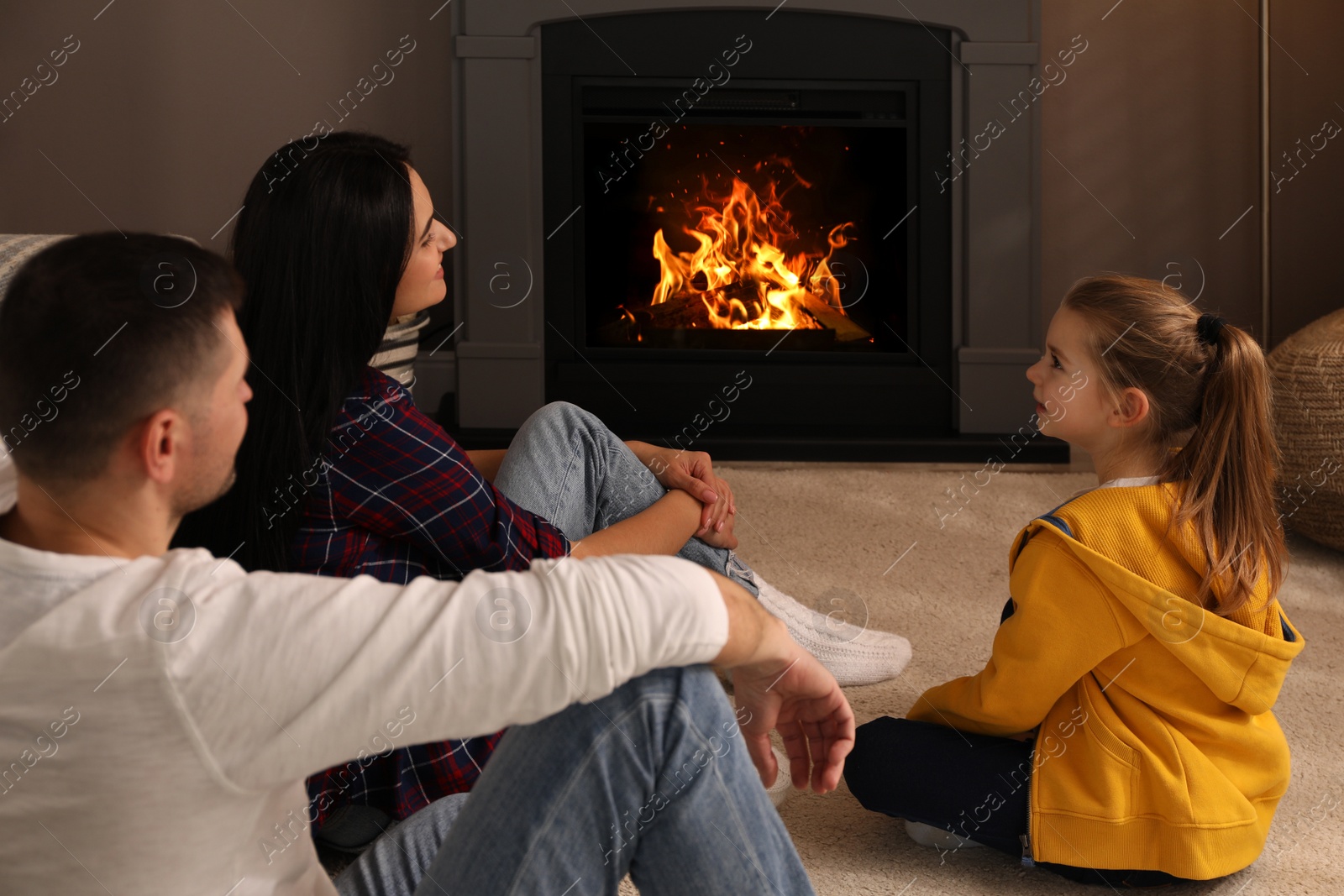 Photo of Happy family spending time together near fireplace at home