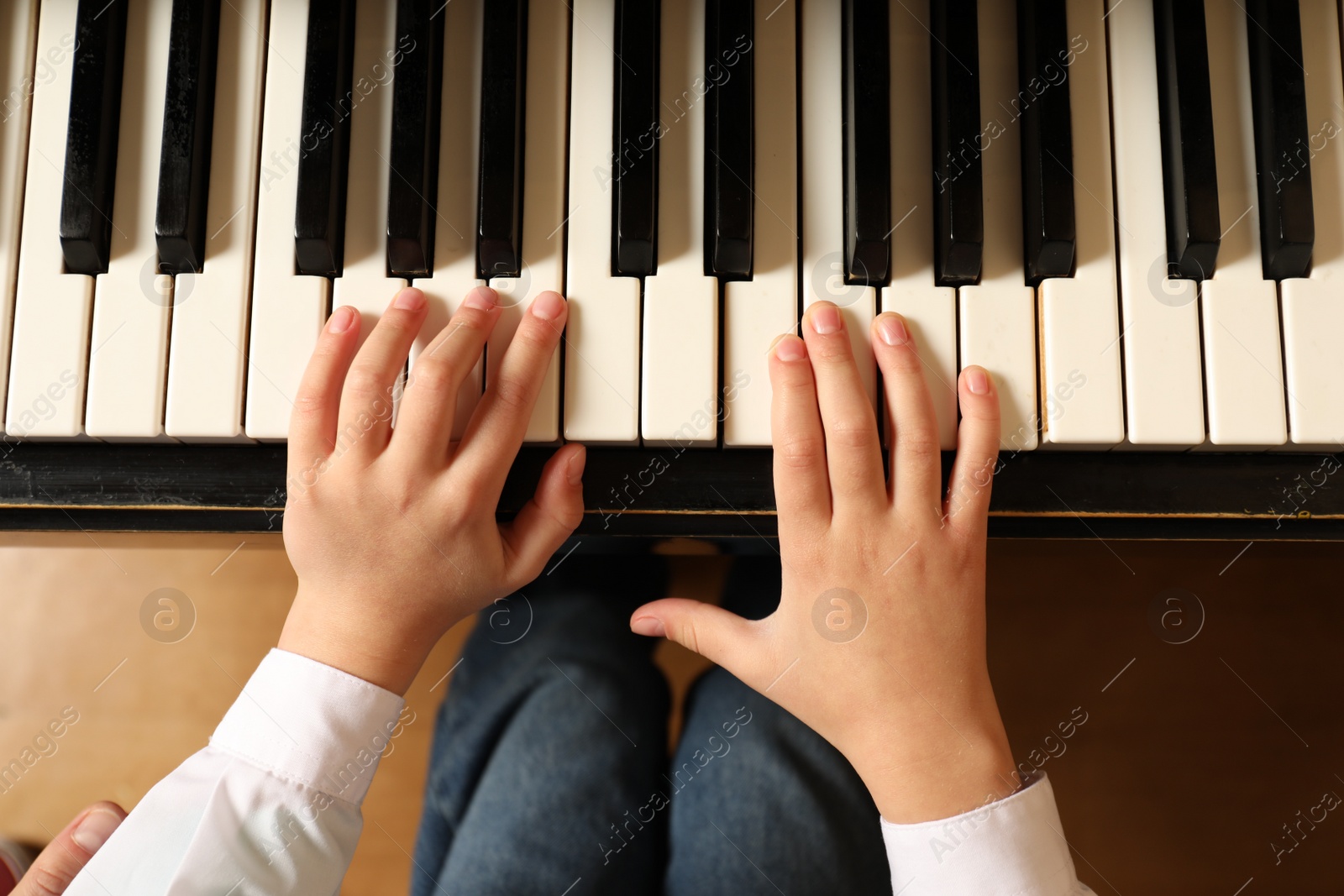 Photo of Little child playing piano, above view. Music lesson