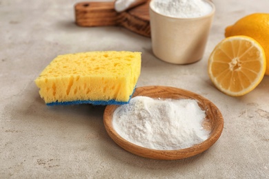 Bowl with baking soda and sponge on gray table