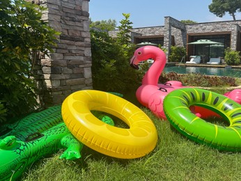Photo of Different inflatable rings and floats on green grass near swimming pool. Luxury resort