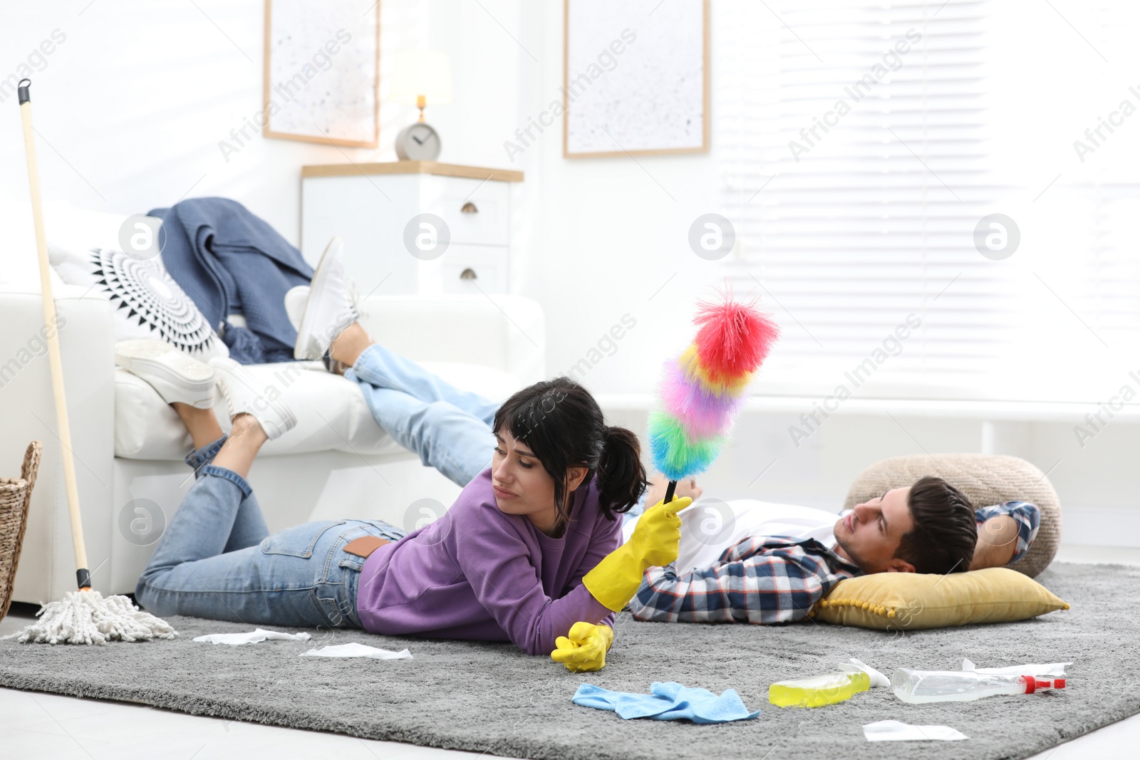 Photo of Lazy couple procrastinating while cleaning at home