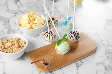 Tasty colorful cake pops on white marble table