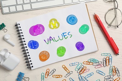 Concept of core values. Notebook with different images and stationery on white wooden table, flat lay