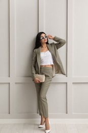 Photo of Full length portrait of beautiful woman in formal suit near light grey wall. Business attire