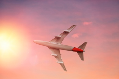 Airplane flying in sky at sunrise. Air transportation