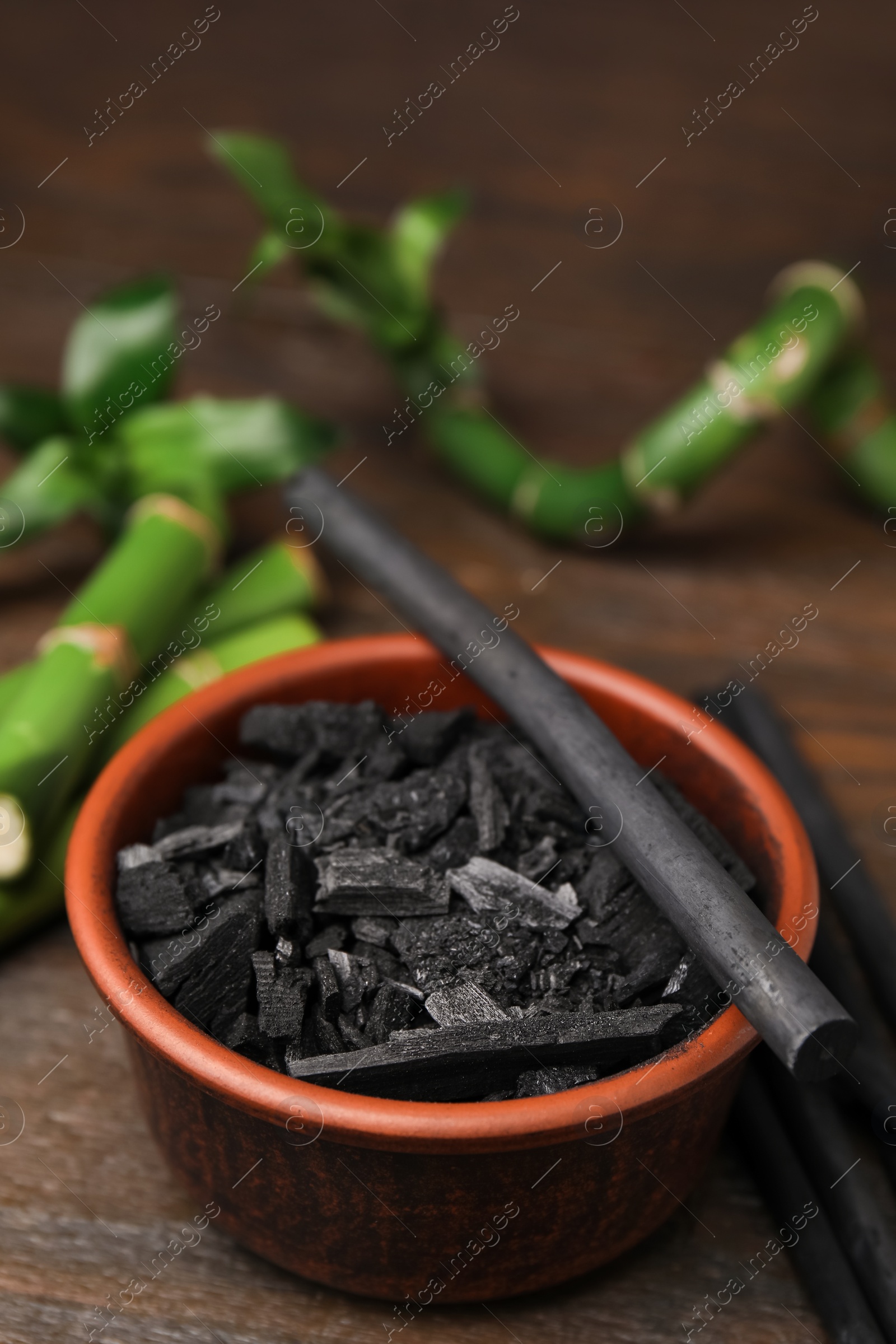 Photo of Fresh bamboo and charcoal on wooden table, closeup