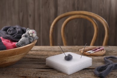 Felting tools, wool and toy cat on wooden table