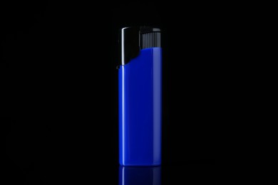 Photo of Blue plastic cigarette lighter on black background, closeup