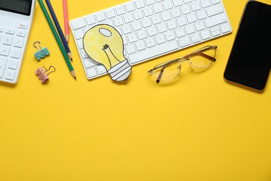Photo of Flat lay composition with computer keyboard, stationery, paper lamp bulb and smartphone on yellow background. Space for text