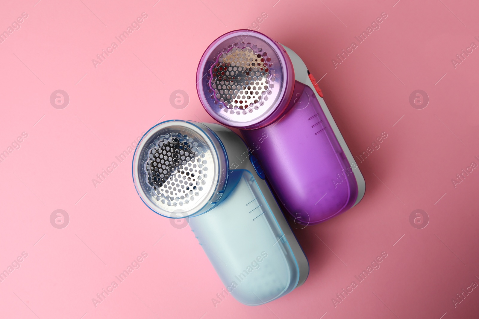 Photo of Modern fabric shavers on pink background, flat lay