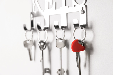 Metal key holder on light wall indoors, closeup
