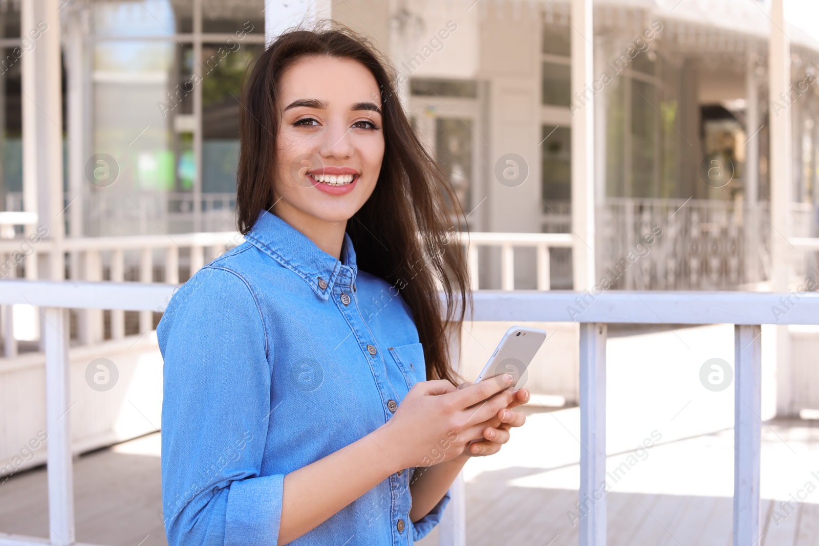 Photo of Young woman using phone outdoors on sunny day