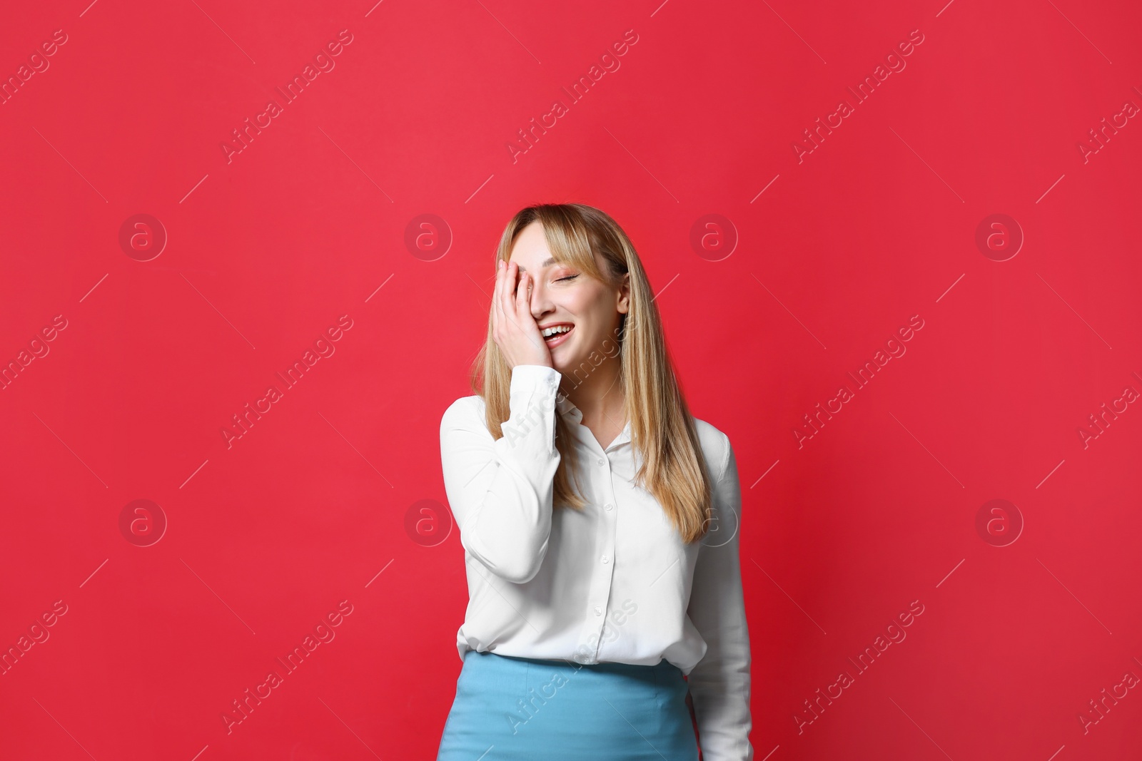 Photo of Beautiful young woman laughing on red background. Funny joke