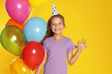 Photo of Happy girl with balloons on yellow background. Birthday celebration