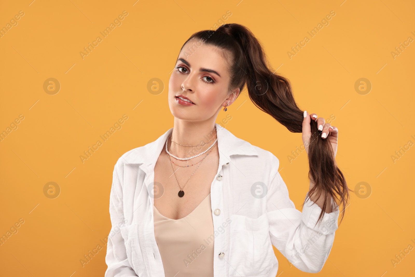 Photo of Beautiful woman with elegant jewelry on orange background