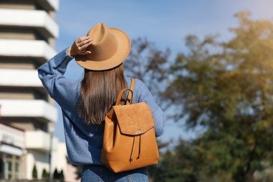 Photo of Young woman with stylish backpack on autumn day, back view. Space for text