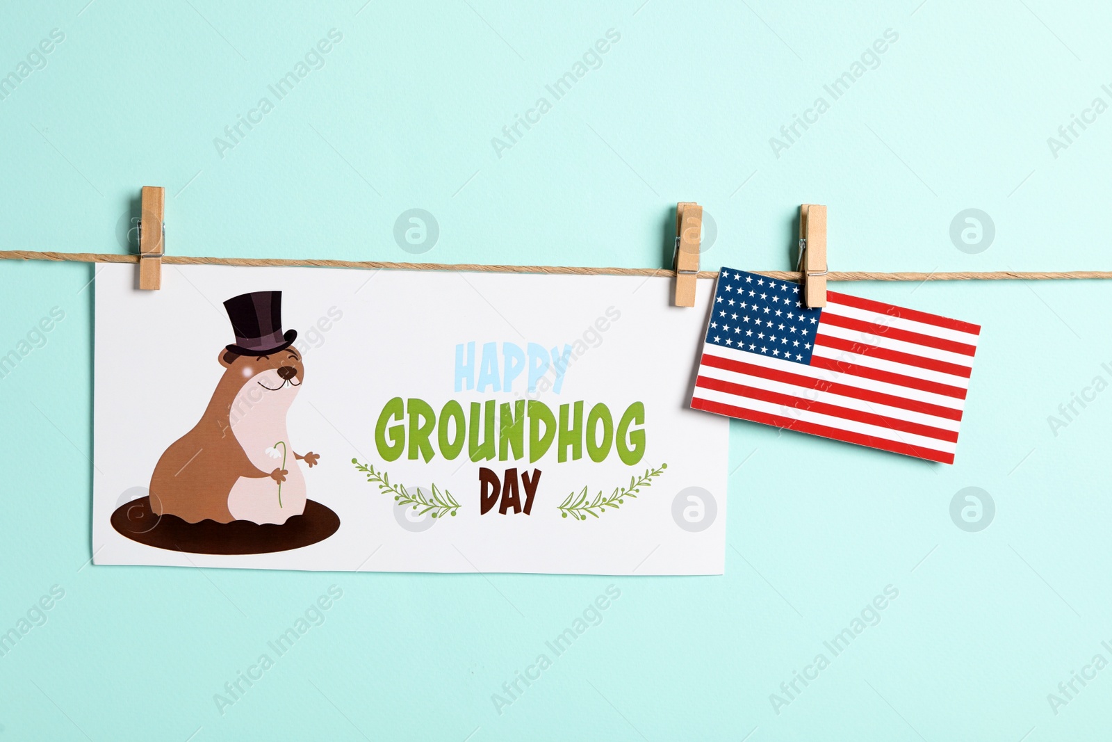 Photo of Happy Groundhog Day greeting card and American flag hanging on turquoise background