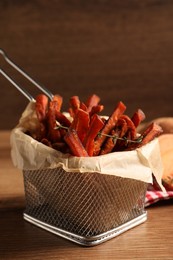 Photo of Frying basket with sweet potato fries on wooden table