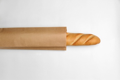 Photo of Paper bag with baguette on white background, top view. Space for design