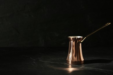 Photo of Beautiful copper turkish coffee pot on black table. Space for text