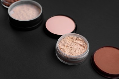 Photo of Different face powders on black background, closeup