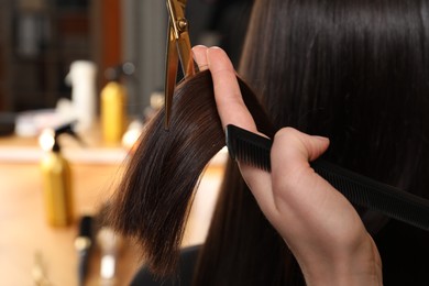 Photo of Hairdresser cutting client's hair with scissors in salon, closeup