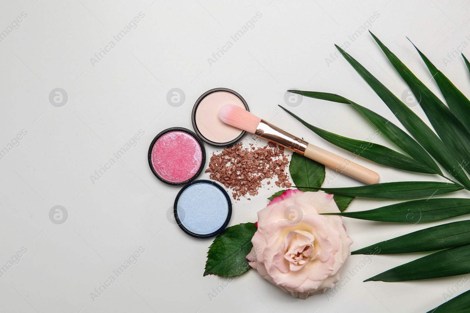 Photo of Flat lay composition with makeup brush, cosmetic products  and rose on white background