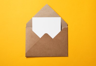 Photo of Blank sheet of paper in open letter envelope on orange background, top view