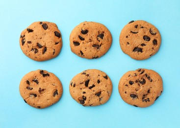 Photo of Many delicious chocolate chip cookies on light blue background, flat lay