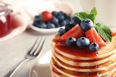 Plate with pancakes and berries on table, closeup