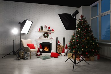 Photo of Beautiful Christmas themed photo zone with professional equipment, tree and fireplace in room