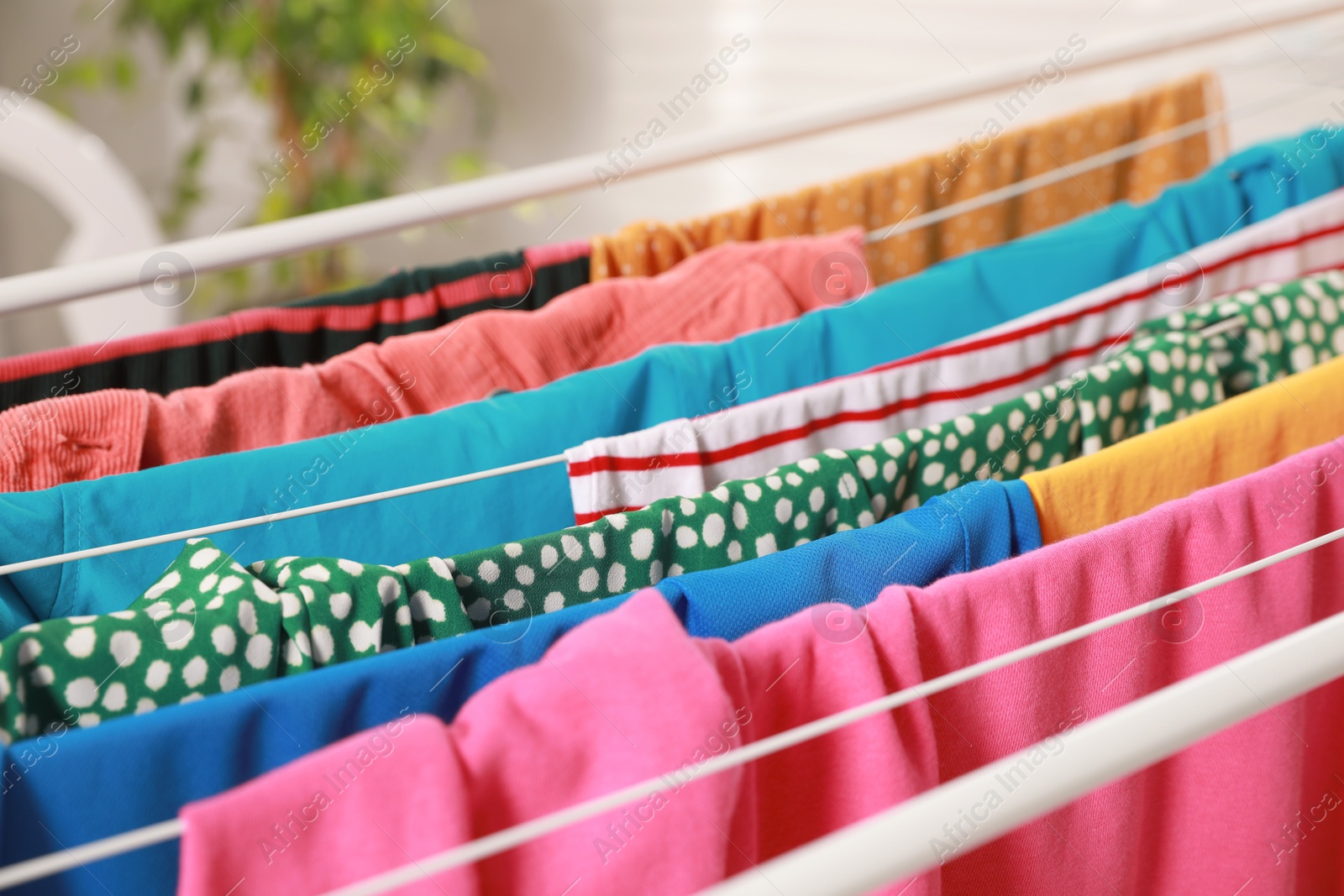 Photo of Clean laundry hanging on drying rack indoors, closeup