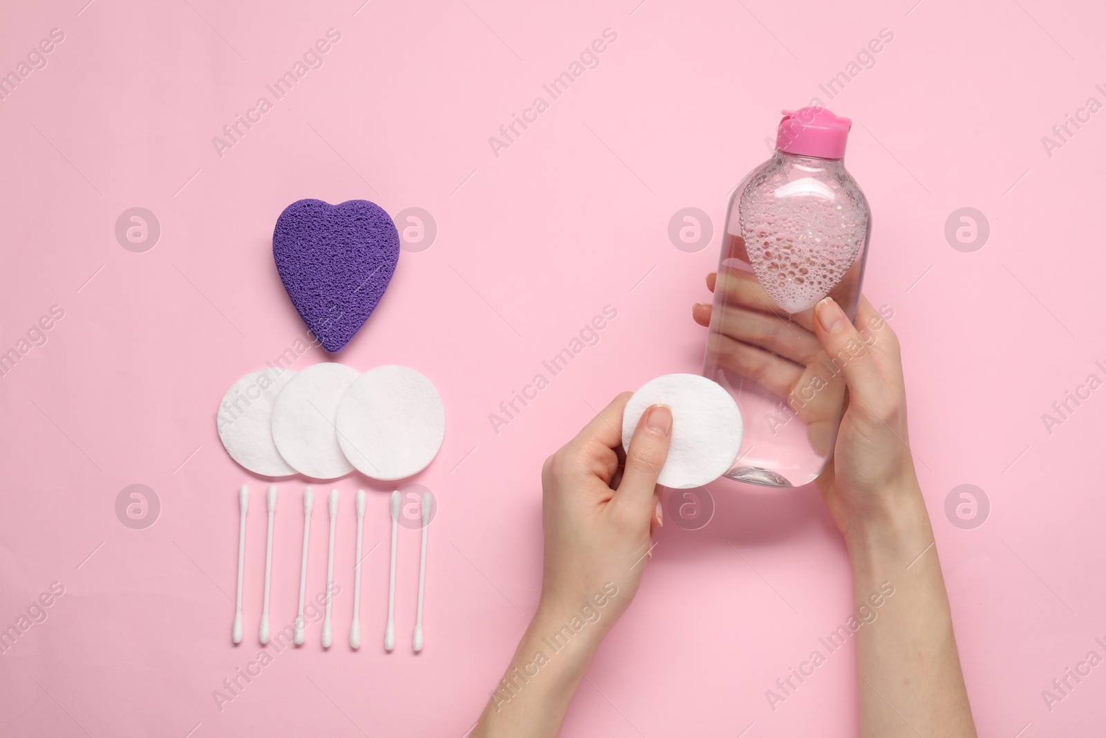 Photo of Woman with makeup remover, cotton pads, buds and sponge on pink background, top view