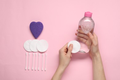 Photo of Woman with makeup remover, cotton pads, buds and sponge on pink background, top view