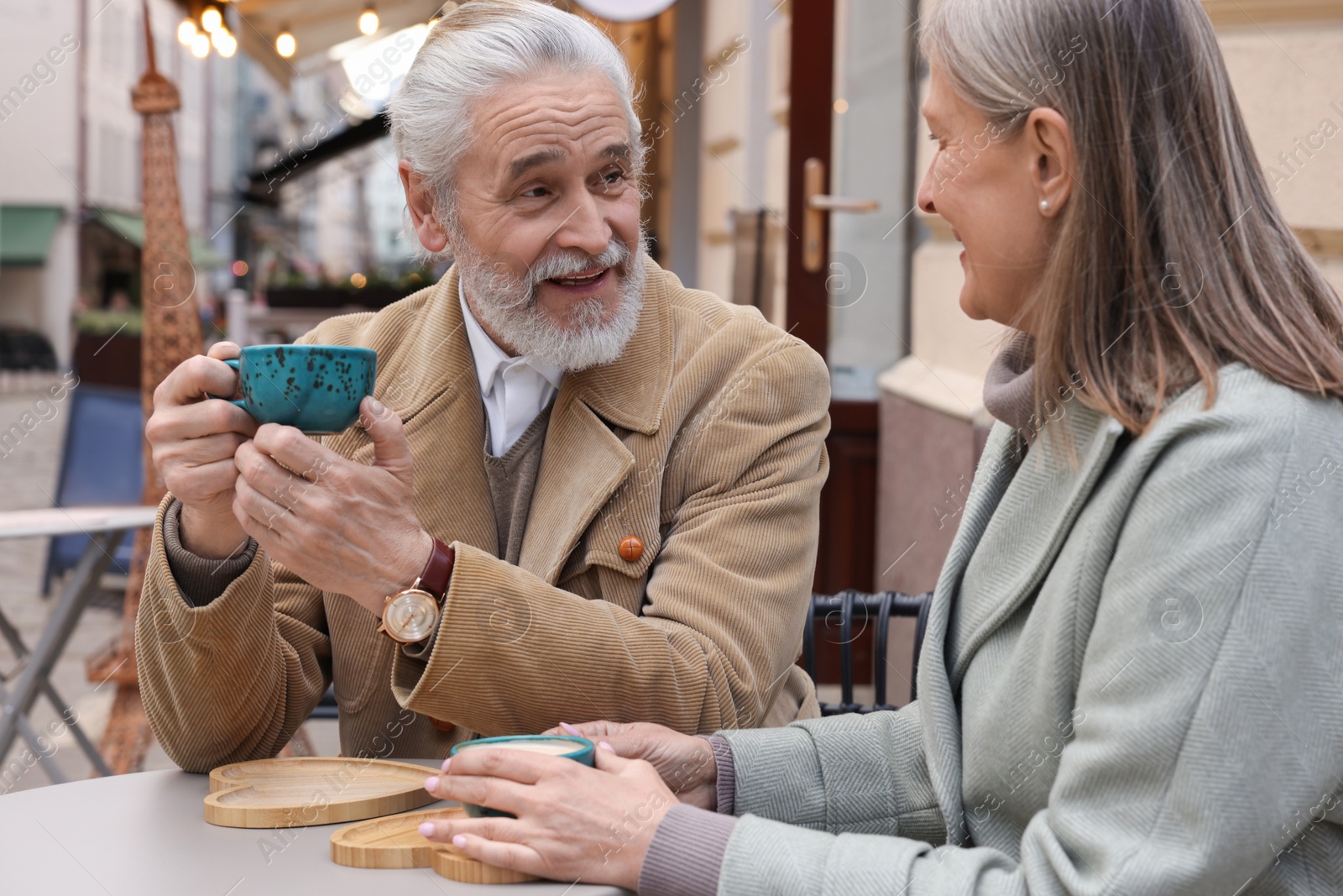 Photo of Portrait of affectionate senior couple drinking coffee in outdoor cafe