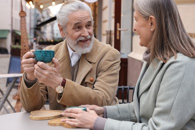 Photo of Portrait of affectionate senior couple drinking coffee in outdoor cafe